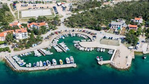 An aerial view of a marina with numerous boats docked, surrounded by residential buildings and a small beach area.