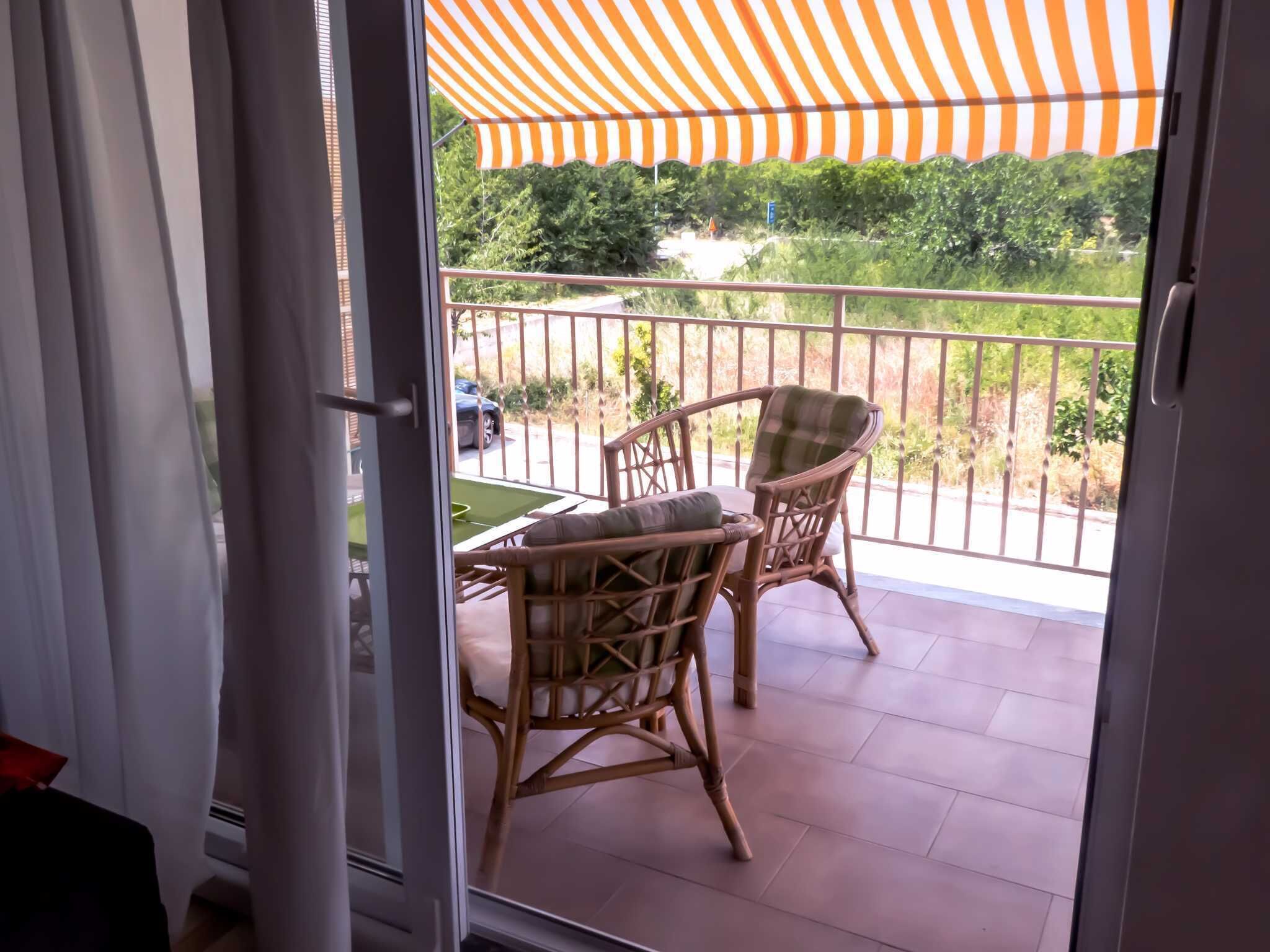 A balcony with wicker chairs and a striped awning.