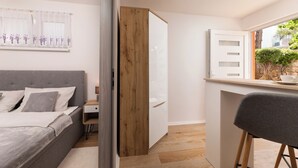 A modern bedroom with a bed, bedside table, and a small desk area. - Studio mit Klimaanlage Grill (Šilo)