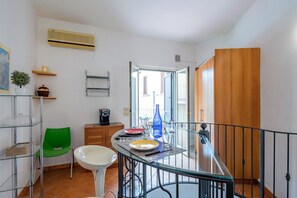 A dining area with a glass table, chairs, and a view of the outside.