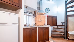 Een keuken met houten kastjes, een witte koelkast, een fornuis en een betegelde spatwand.