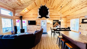 Interior de una cabaña de madera con sala de estar, comedor y cocina.