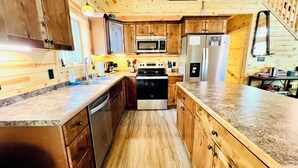 Una cocina compacta con gabinetes de madera, electrodomésticos de acero inoxidable y encimera de granito.