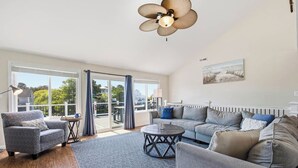 Ein geräumiges Wohnzimmer mit einer großen Couch, einem Couchtisch und einem Deckenventilator.