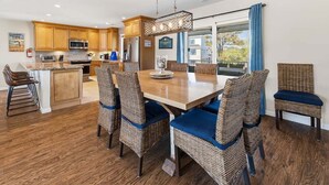 Eine moderne Küche mit Holzausstattung, einer zentralen Kochinsel und einem Essbereich mit Korbstühlen und einem Holztisch.