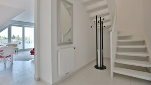 A modern interior with a staircase, a coat rack, and a view through a large window.