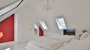 A bedroom with a bed, a TV, a chandelier, and skylights.