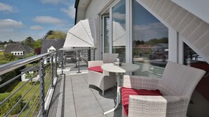 A balcony with wicker furniture, a round table, and a glass railing.
