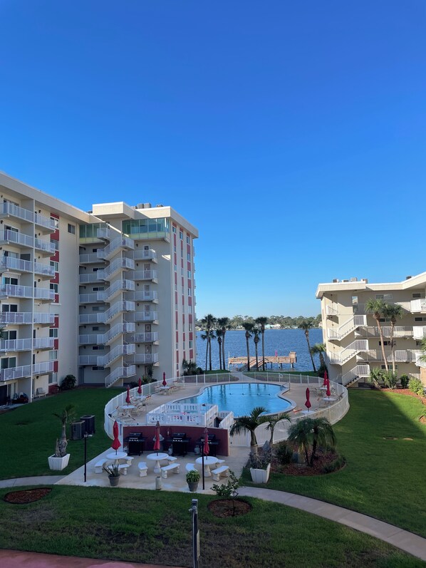 A hotel with a swimming pool, outdoor seating, and a view of the water.