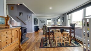 A spacious kitchen with wooden cabinets, a dining area with a table and chairs, and a large window providing natural light. - Vermont Vacation Rental: Hot Tub, Near Ski Resorts (Mt Holly)