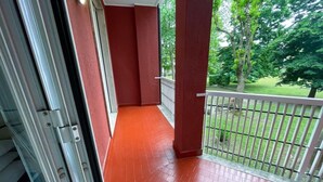 A red-tiled balcony with a white railing, leading to a door.