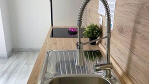 A modern kitchen with a stainless steel sink, a wooden countertop, and a small potted plant.