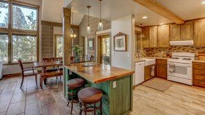 A kitchen with a wooden island, large windows, and a stone backsplash.