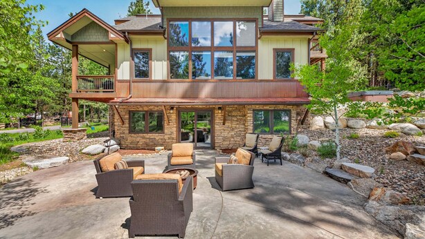 A two-story house with a patio area featuring outdoor furniture.