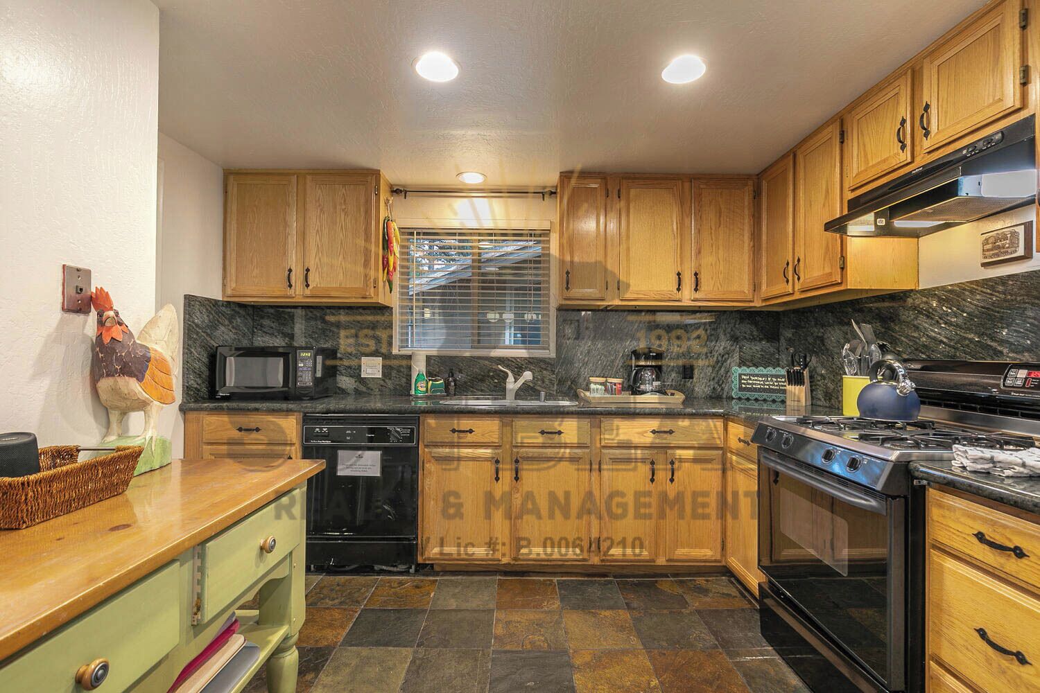 A kitchen with wooden cabinets, a microwave, a sink, a stove, and a window with blinds.