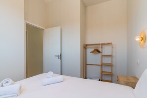 A hotel room with a bed, a wooden wardrobe, and a wall-mounted light fixture. - Villa Roquille, direct beach access (Agde)