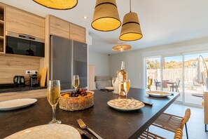 A modern kitchen with a central island, wooden cabinetry, and pendant lighting.