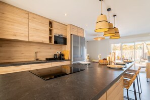 A modern kitchen with wooden cabinets, a central island, and pendant lighting.
