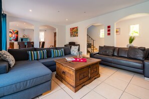 A modern living room with a sectional sofa, a wooden coffee table, and a dining area with a blue cabinet.