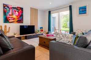 A modern living room with a flat-screen TV, comfortable seating, and artwork on the walls.