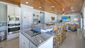 Una cocina moderna con encimeras de granito, electrodomésticos de acero inoxidable y taburetes de bar de madera.