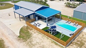 Un edificio moderno con un patio cubierto, piscina y un parque infantil.