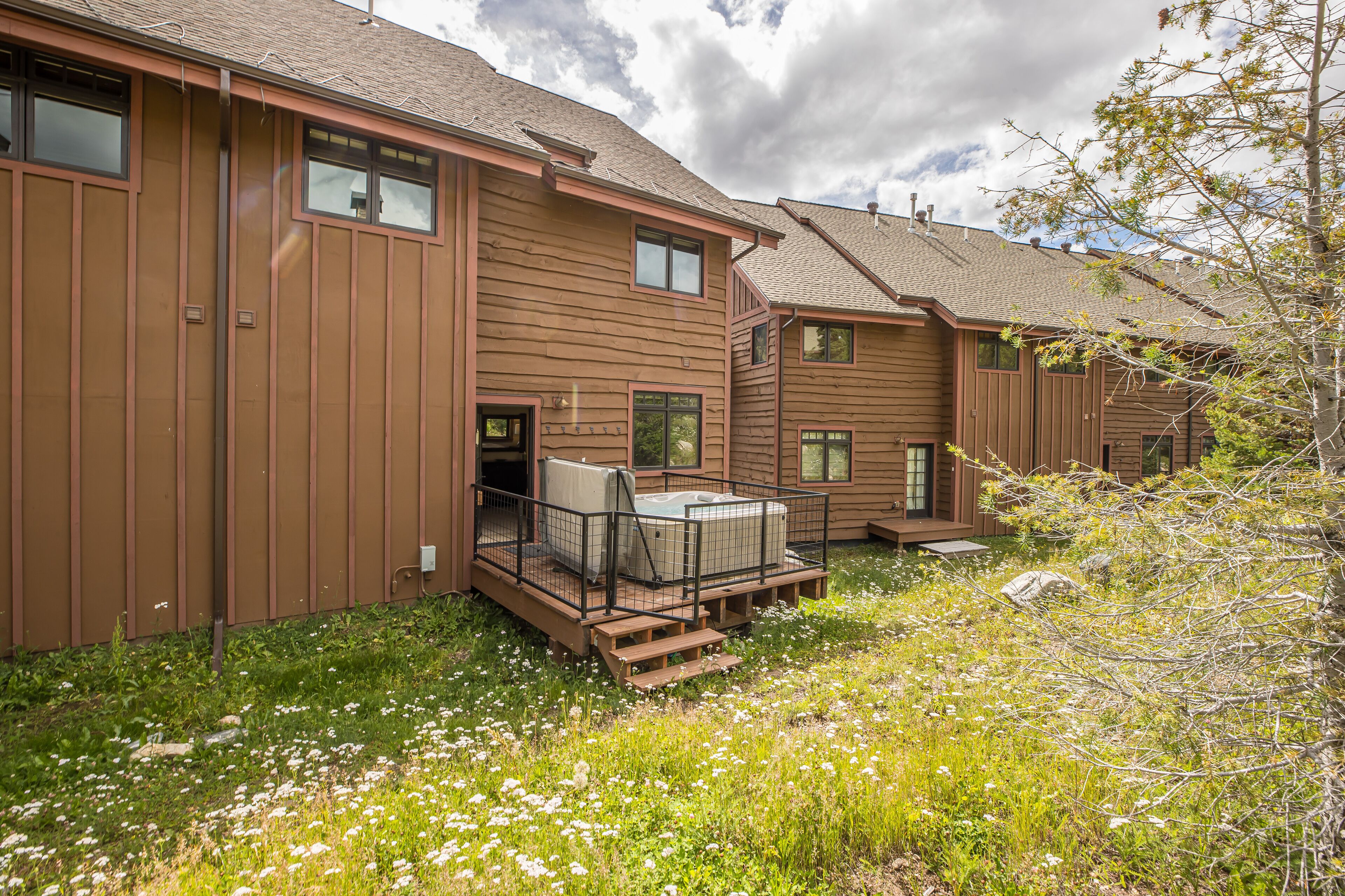 A row of wooden cabins with a hot tub on the patio.