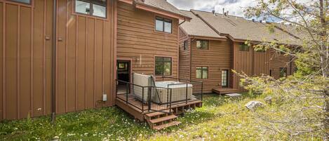 A row of wooden cabins with a hot tub on the patio.