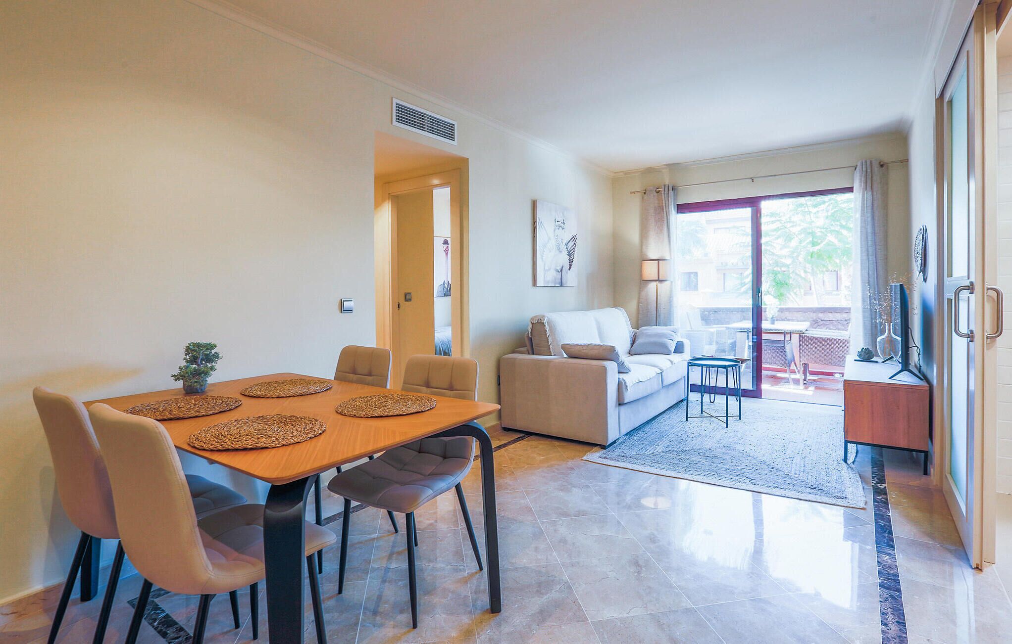 Ein modernes Wohnzimmer mit Essbereich, einer Couch und Blick ins Freie.