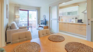 A modern living room with a sofa, two armchairs, and a wooden dining table with woven placemats.