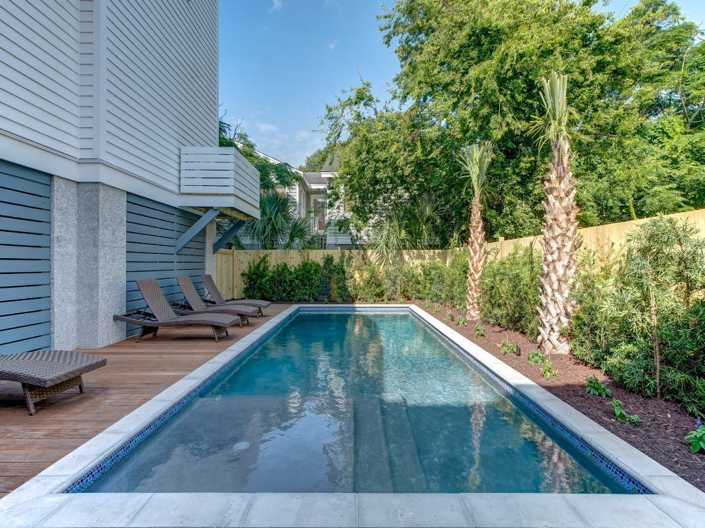 Una piscina rectangular amb una terrassa de fusta i gandules.