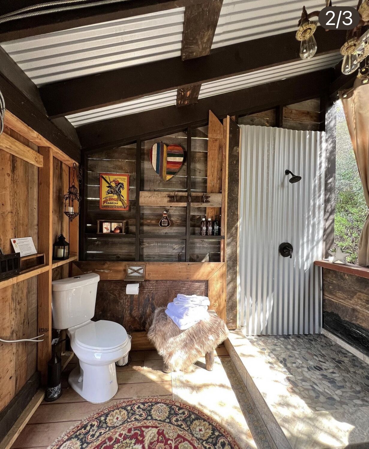 Ein rustikales Badezimmer mit Toilette aus Holz, einem kleinen Hocker und einer Duschkabine.