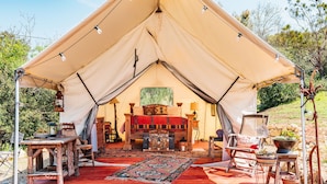 A tent with a central seating area, a rug, and various items on the floor.