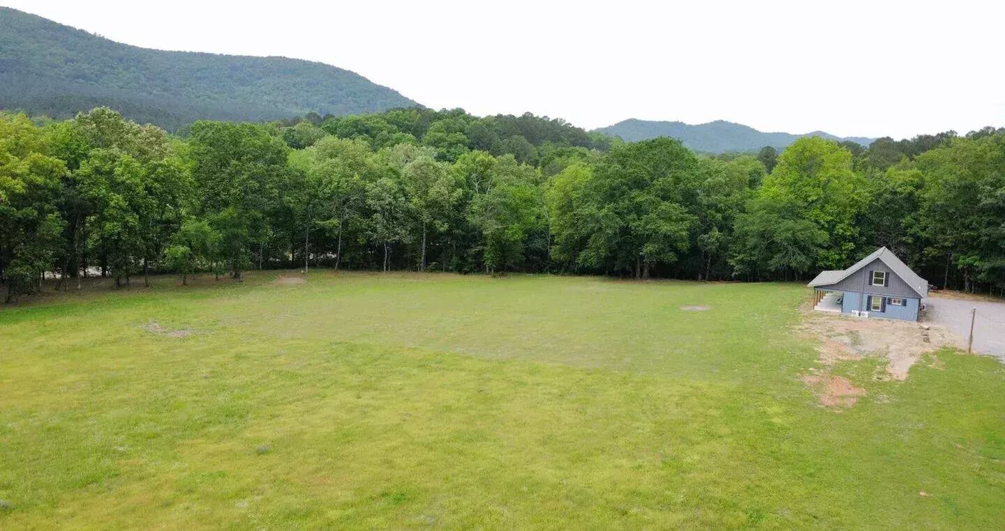 A grassy field with a small house on a hill.