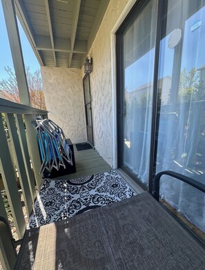 A covered porch with a metal railing, a door leading to a garage, and a patterned rug.