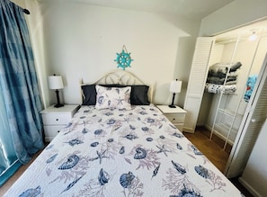 A bedroom with a bed, nightstands, a wardrobe, and a wall decoration.