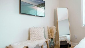 Una habitación con un banco de madera, un espejo y un jarrón con flores secas.
