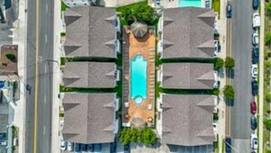 Vista aérea de un área residencial con cuatro casas, una piscina central y una carretera.