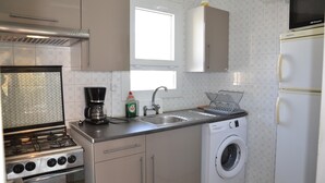 A compact kitchen with a gas stove, a washing machine, a sink, and a microwave. - Alicante 1 - L'Estartit, Center (Estartit (L´))