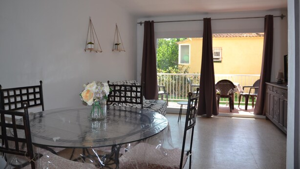 A dining area with a glass table, chairs, and a sofa. There are curtains and a view of the outside. - Alicante 1 - L'Estartit, Center (Estartit (L´))