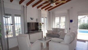 A modern living room with a white sofa set, a coffee table, and a flat-screen TV. - CASA JOSI with awesome views to the sea at Monte Pego (Pego)