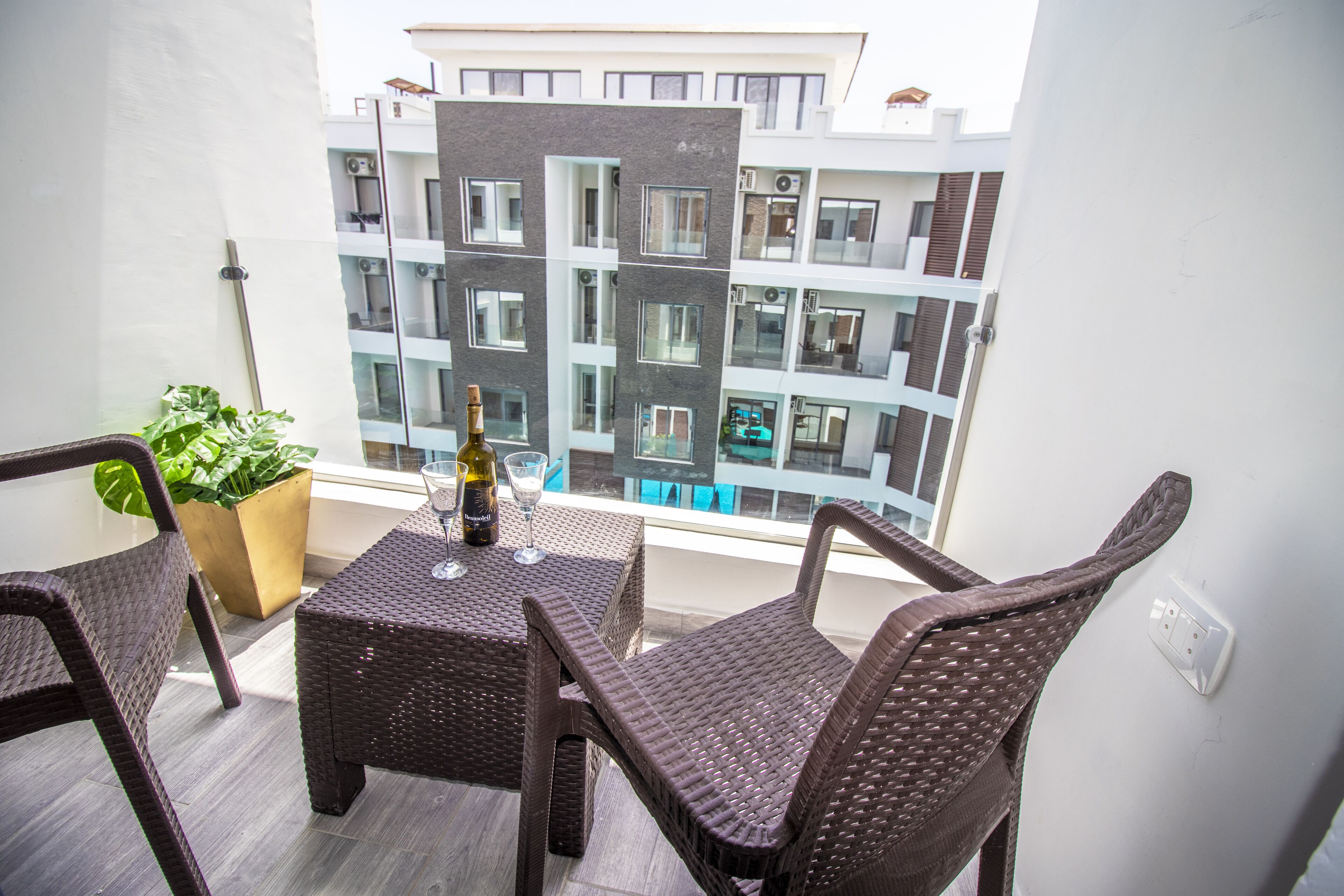 Un balcon agrémenté de meubles en osier, une bouteille de vin et une plante en pot.
