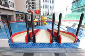 A swimming pool with a boat-shaped structure in the center, surrounded by a blue-tiled deck. - Bali Deluxe Melaka By I Housing  (Malacca City)