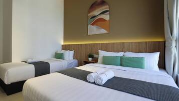 A hotel room with two beds, a wooden headboard, a wall-mounted painting, and a potted plant.