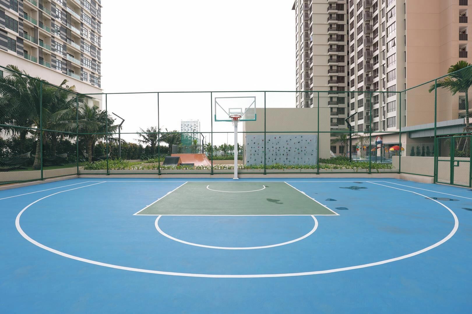 An outdoor basketball court surrounded by high-rise residential buildings.