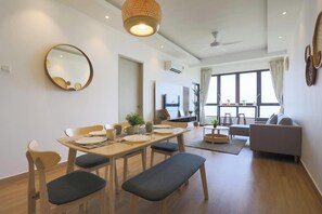 A modern living room with a sofa, a dining area with a table and chairs, a ceiling fan, and a large window with curtains. - Bali Deluxe Melaka By I Housing  (Malacca City)