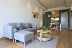 Una sala de estar moderna con un sofá gris, una mesa de centro redonda y un comedor con una mesa y sillas.