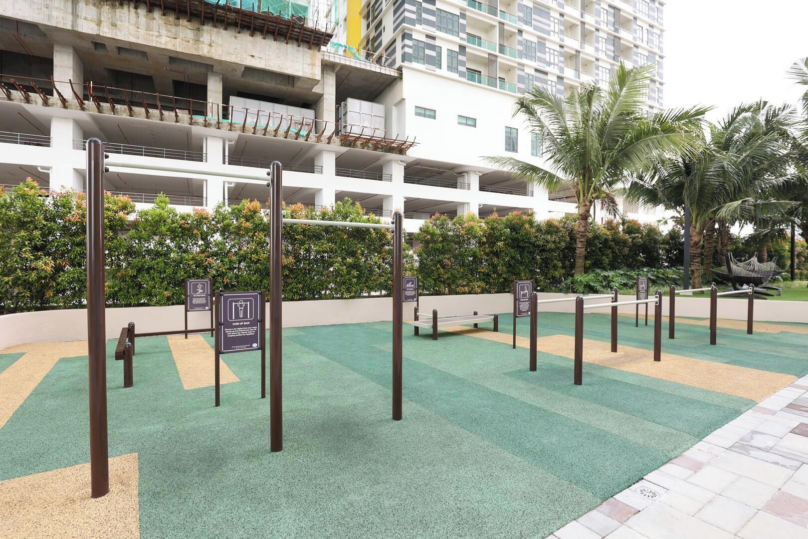 A multi-level parking structure with a green artificial turf area in the foreground, surrounded by greenery and palm trees.