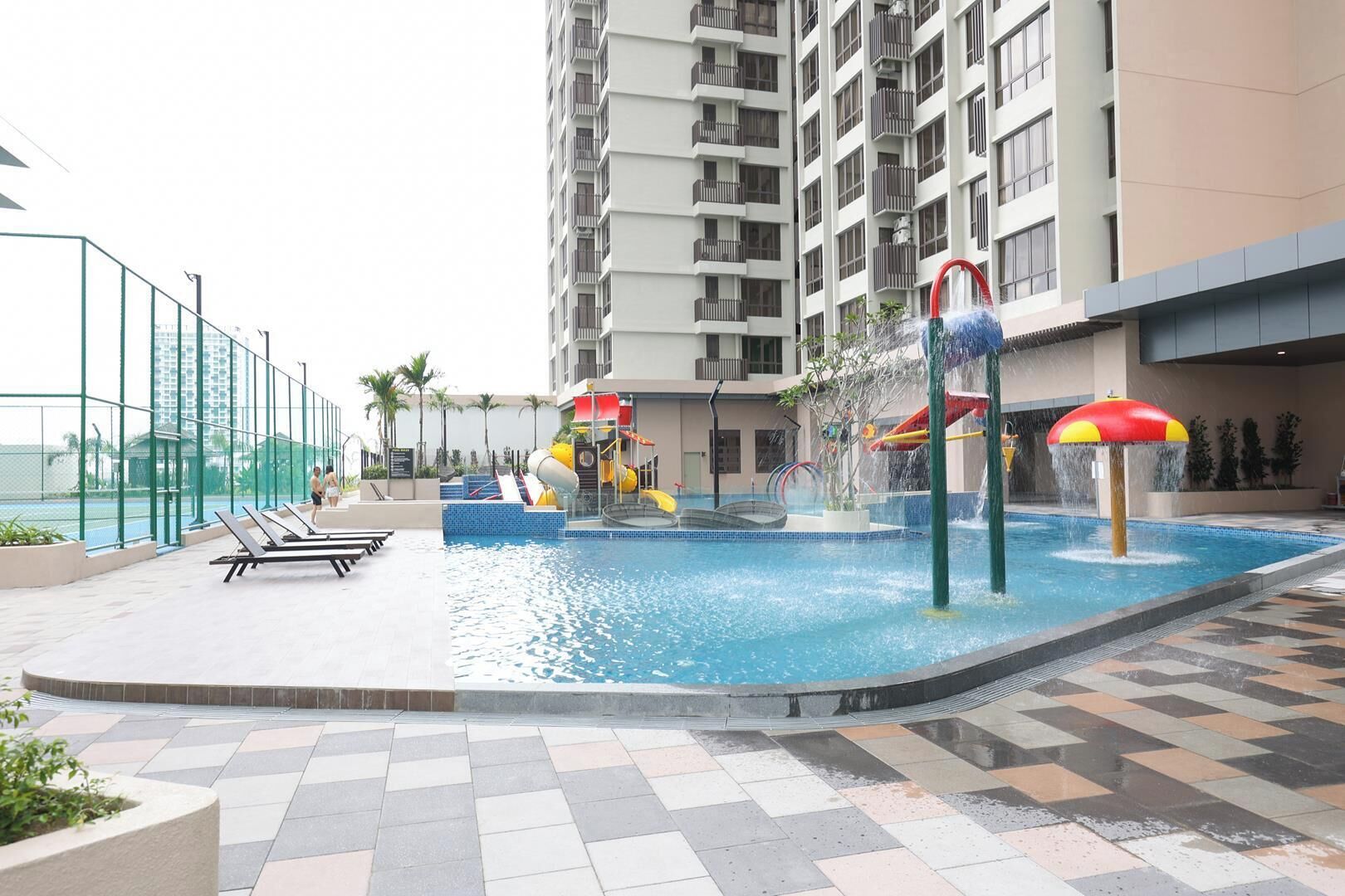 Uma área de piscina no terraço com um toboágua, espreguiçadeiras e vista para um prédio alto.