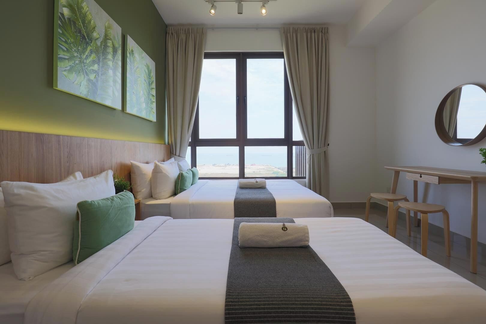 Une chambre d’hôtel avec deux lits, un bureau et vue sur la plage.